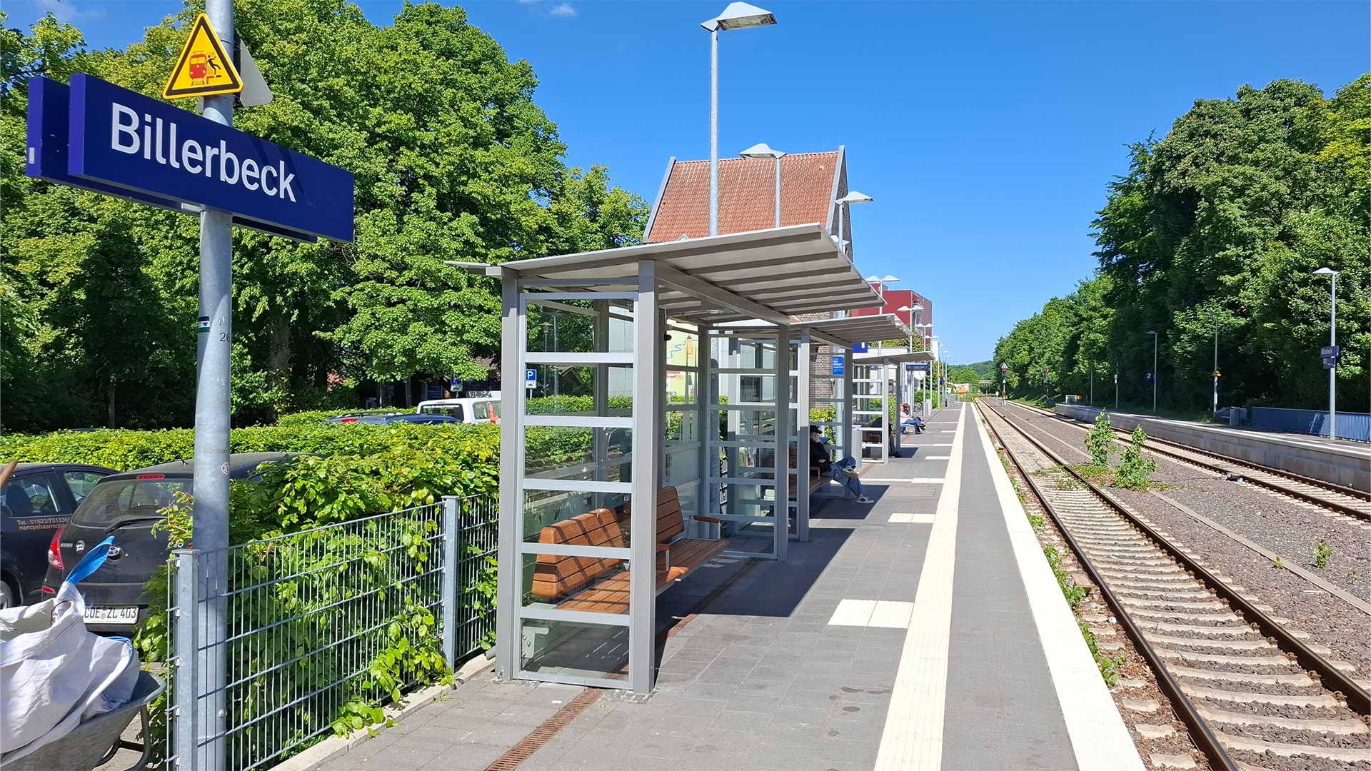 Überdachte Wartebereiche am Bahnsteig Billerbeck mit Sitzbänken, klarer Sommertag, Blick entlang der Gleise Richtung Ausfahrt