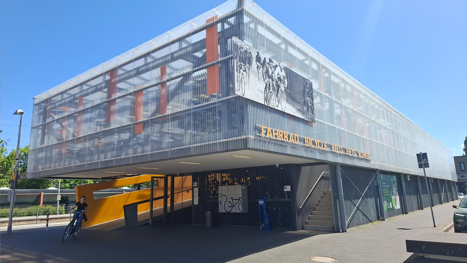 Mehrstöckiges Fahrradparkhaus am Bahnhof Emsdetten mit transluzenter Fassade und Rampen, Schriftzug „Fahrrad Bicycle Velo Fiets Rover“