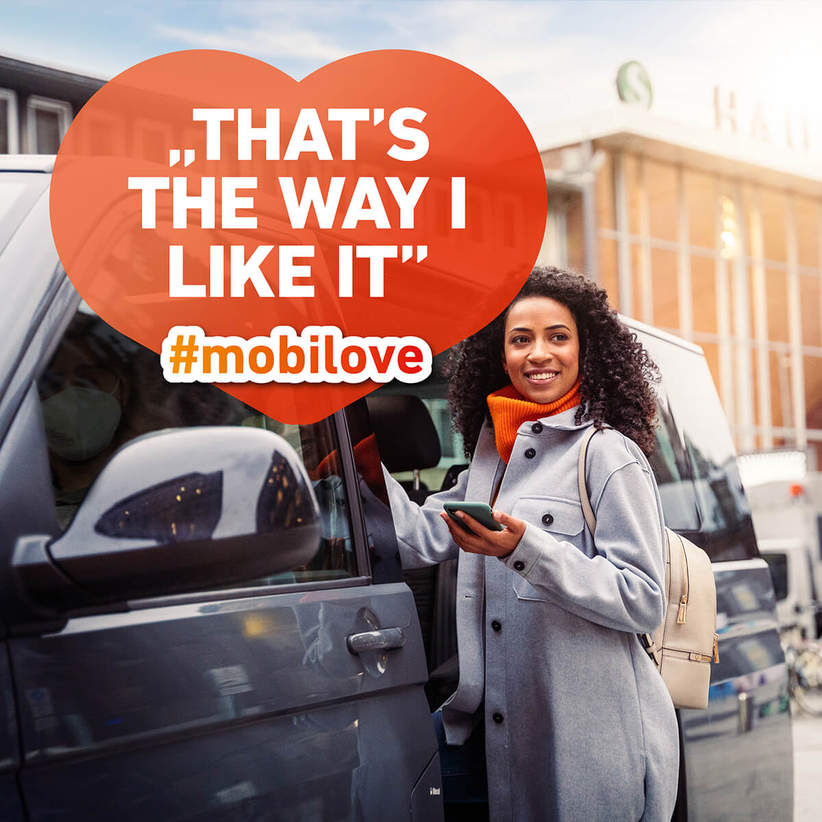 Mobilove-Visual: Frau steht lächelnd mit ihrem Smartphone neben einem Van, die Herzchen-Kommentarblase im Bild: "That's the way I like it"