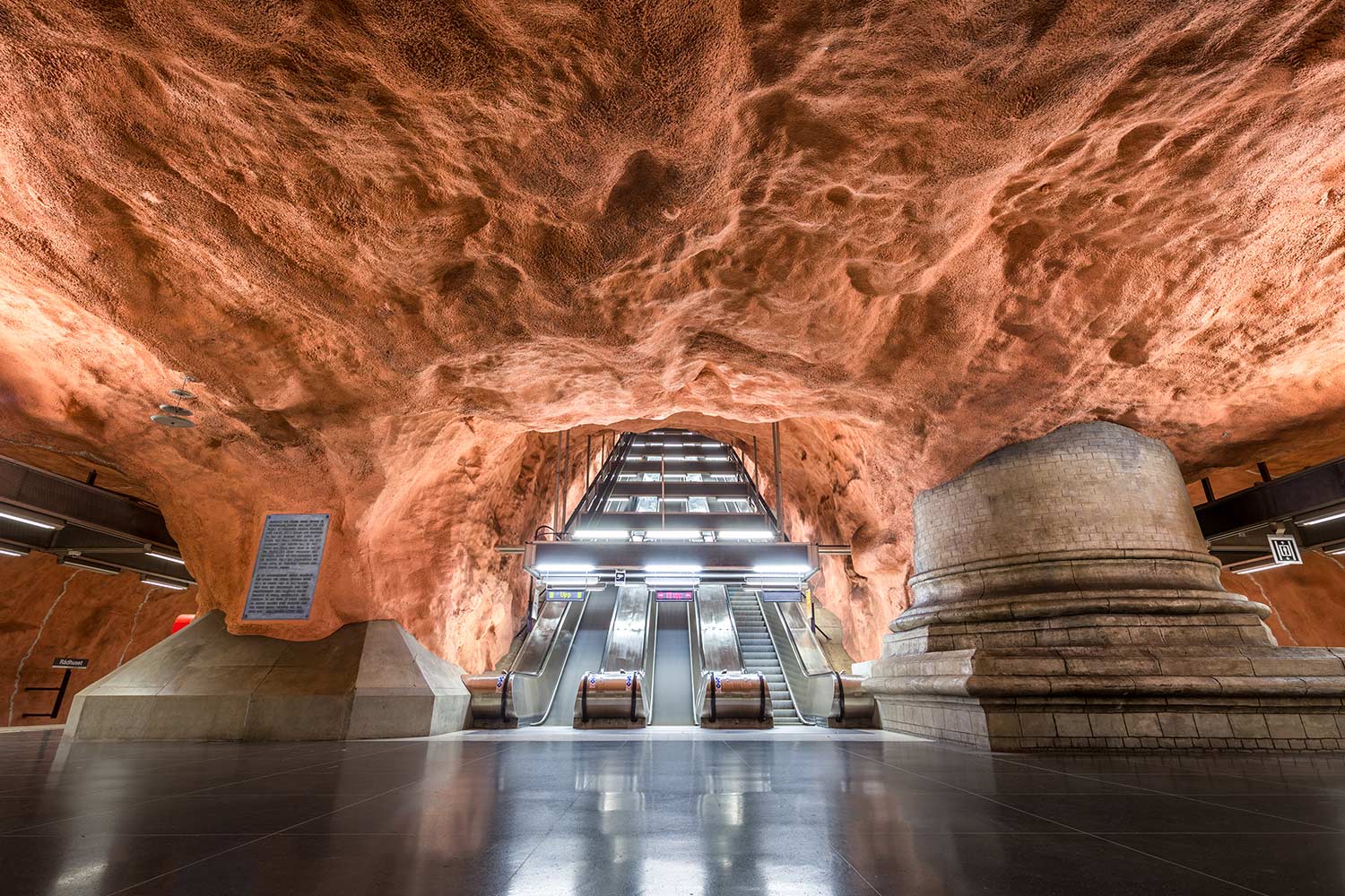 Rolltreppen in einer Stockholmer U-Bahn-Station, deren Decke wie eine Sandsteinhöhle gestaltet ist.