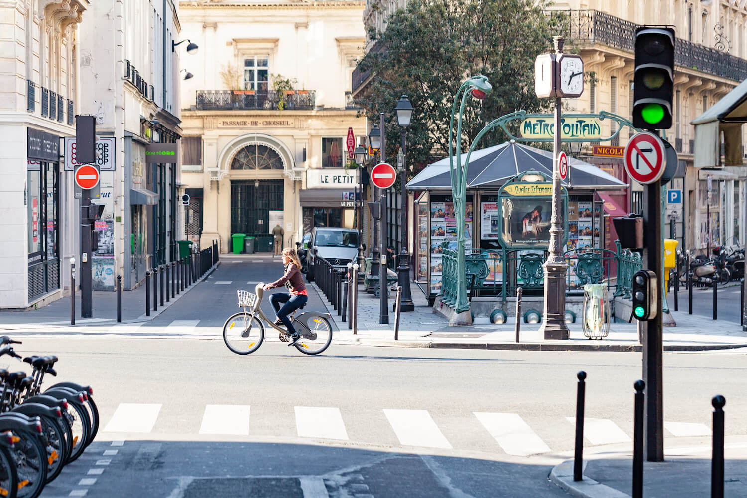 Frau fährt durch die Straßen von Paris, im Hintergrund sind einige Häuser und Läden.