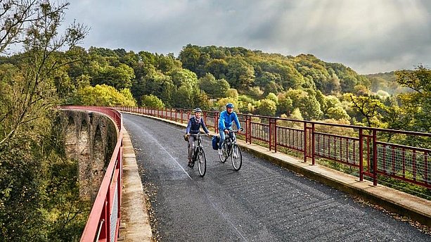 Zwei Personen fahren mit dem Fahrrad über das Viadukt Ruhrstrasse auf dem PanoramaRadweg niederbergbahn Essen. PanoramaRadweg niederbergbahn, Essen