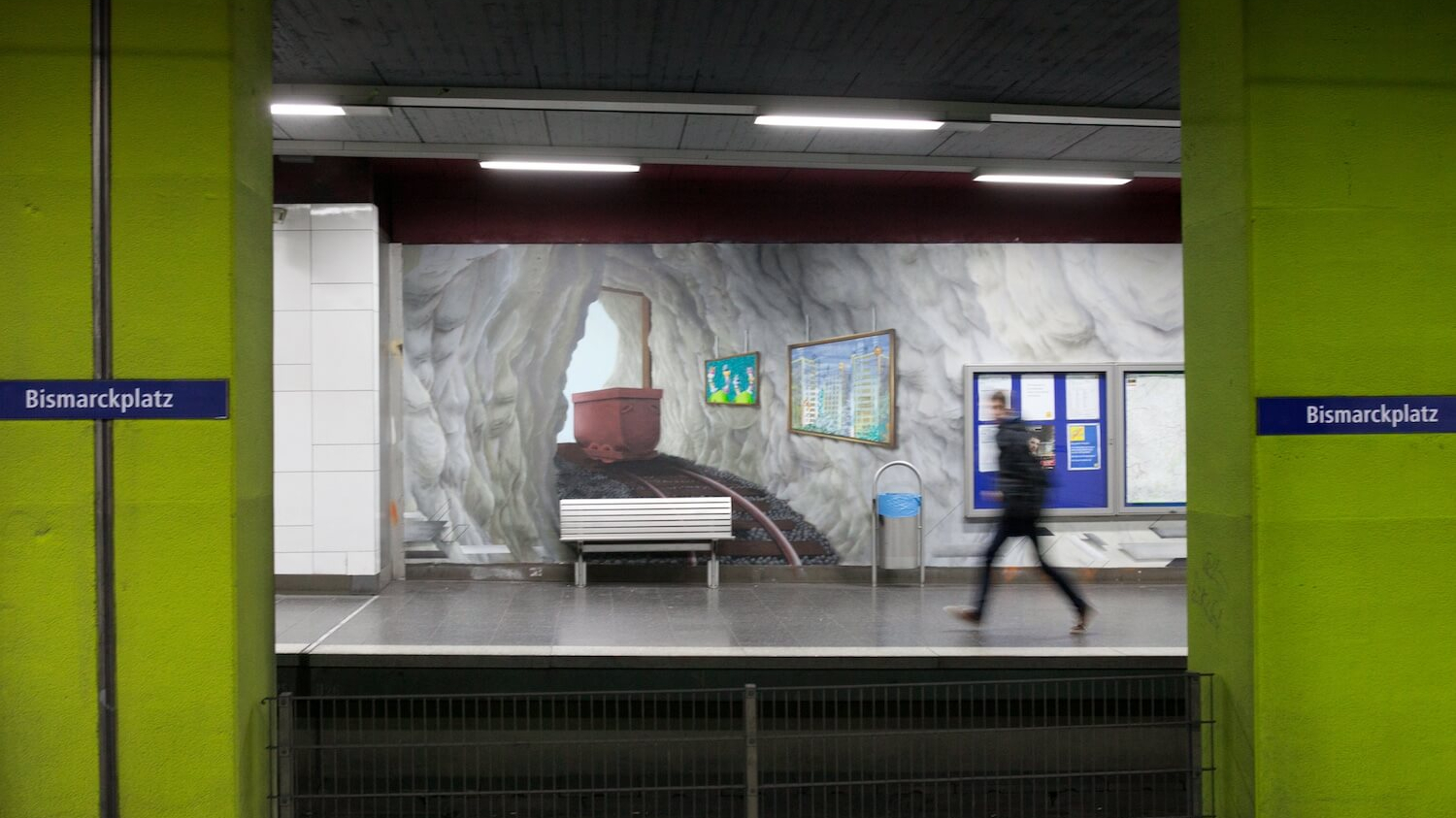 Im U-Bahn-Bereich der Haltestelle Essen-Bismarckplatz sieht man zwischen grüngestrichenen Wänden ein Wandgemälde, das Schienen und Wagons in einem Bergwerk darstellen.