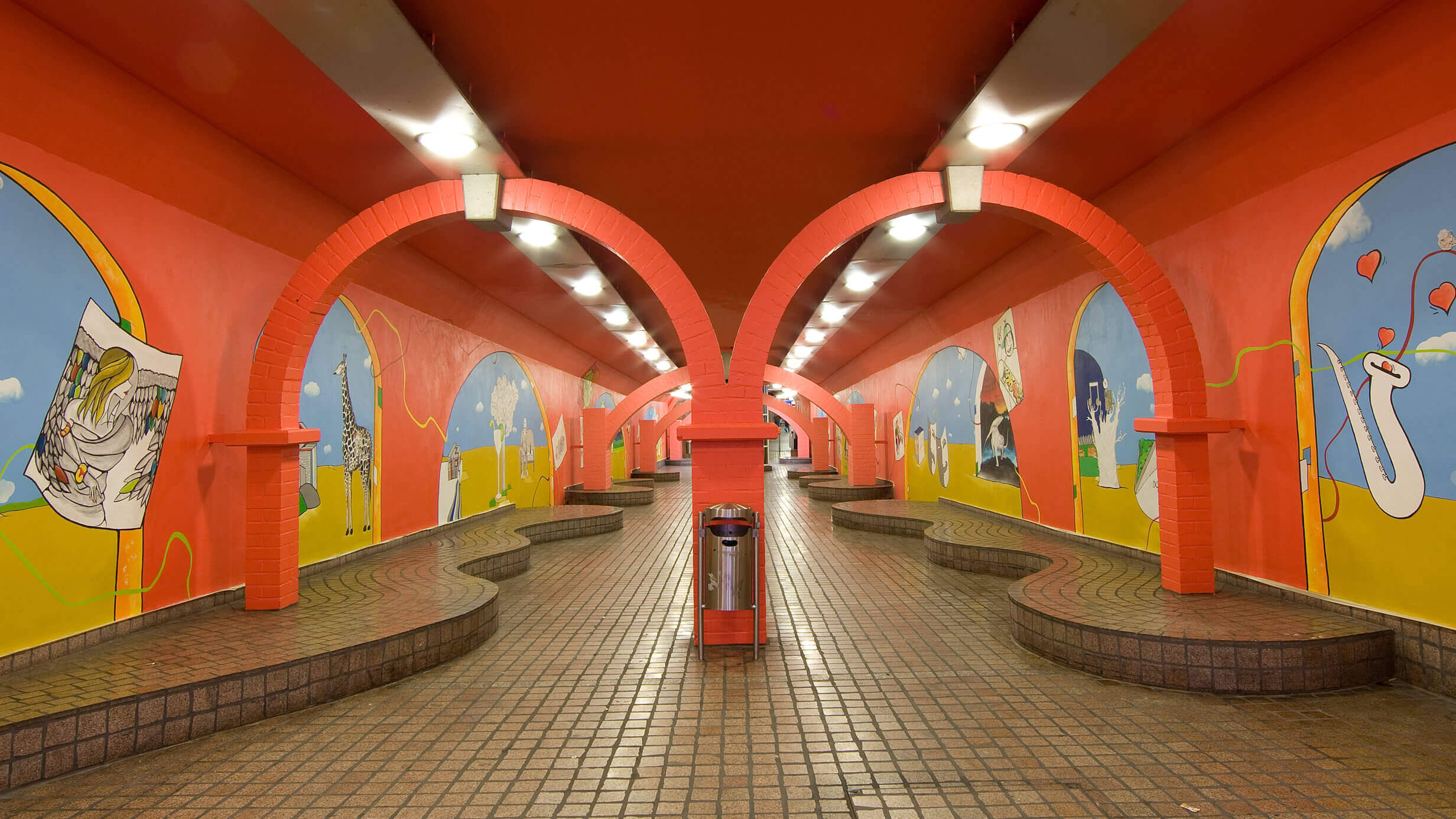 Die Gänge in der Essener U-Bahn Station Viehofer Platz, die leuchtend orange und mit Tieren bemalt sind.