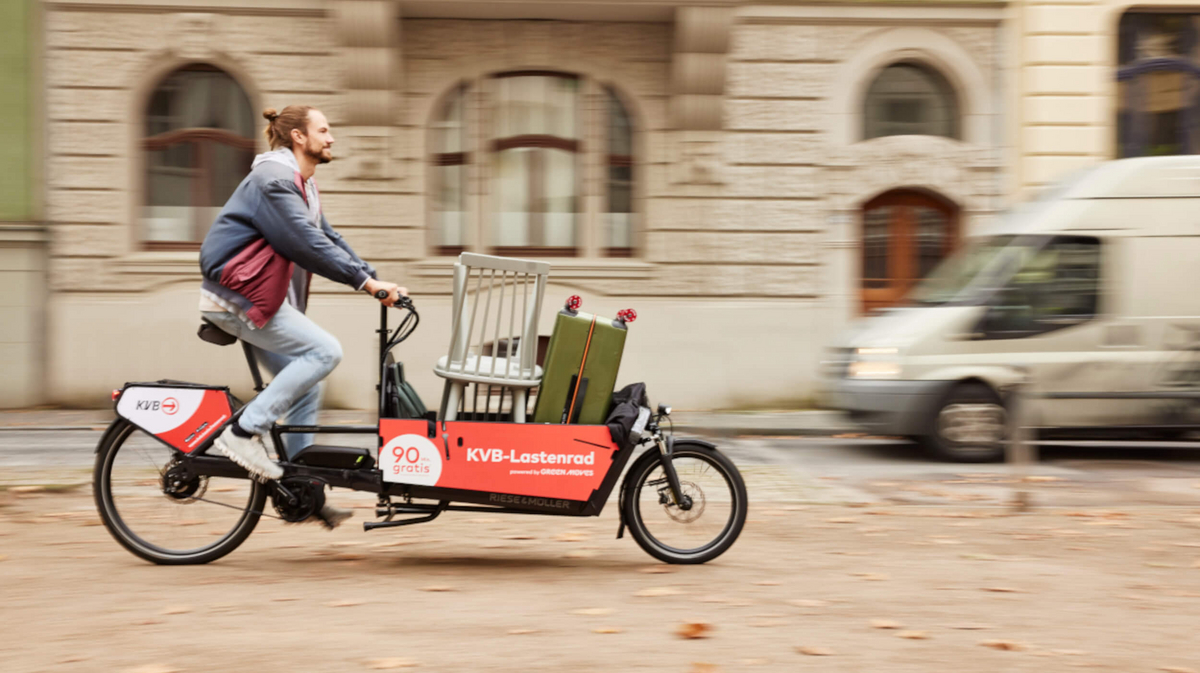 Ein jugner Mann fährt auf einem Lastenrad im Kölner Stadtgebiet.