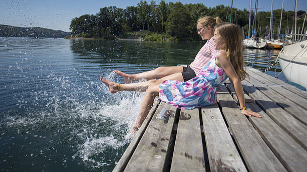 Zwei junge Mädchen sitzen auf einem Steg am Sorpesee Sundern-Langscheid. Sorpesee, Sundern-Langscheid