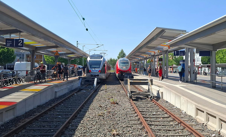 Moderne Bahnsteige am Bahnhof Iserlohn mit zwei einfahrenden Regionalzügen, Fahrgäste steigen ein und aus, klare Sommeratmosphäre