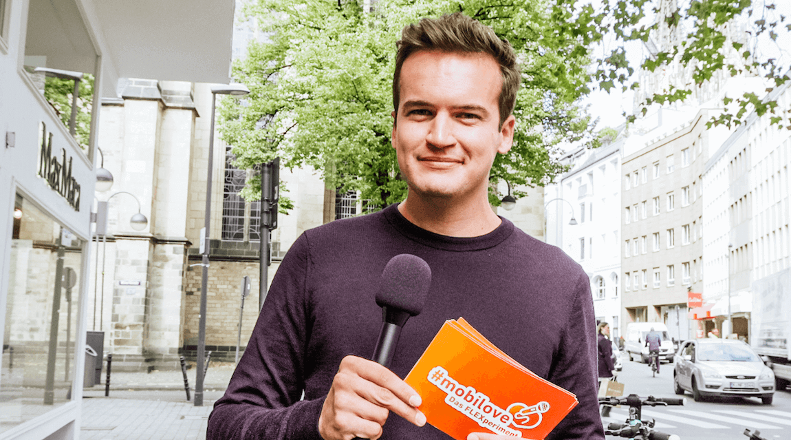 Moderator Fritz Schaefer steht mit mobilove-Moderationskarten auf der Straße und blickt in die Kamera.