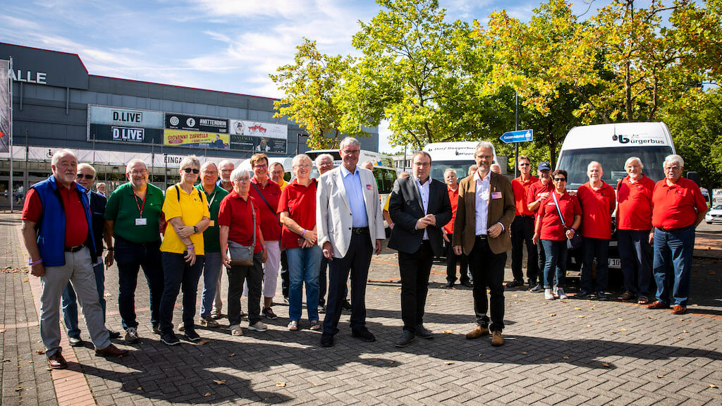 Rolf Peuster, Geschäftsführer Pro Bürgerbus NRW e.V., Oliver Krischer, Minister für Umwelt, Naturschutz und Verkehr des Landes Nordrhein-Westfalen, und Franz Heckens, Vorsitzender Pro Bürgerbus NRW e.V., gemeinsam mit Bürgerbusfahrer*innen aus NRW.