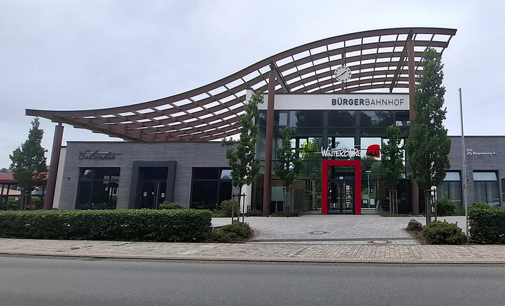 Bürgerbahnhof Winterberg mit markanter geschwungener Dachkonstruktion und zentralem Eingang, urbanes Empfangsgebäude an der Tourist‑Info