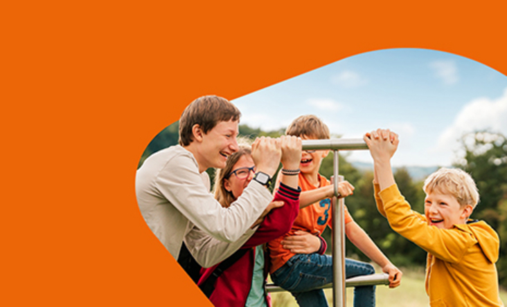 Zu sehen ist eine Familie, welche auf einem Spielplatz zusammen die Attraktionen erkundet. 