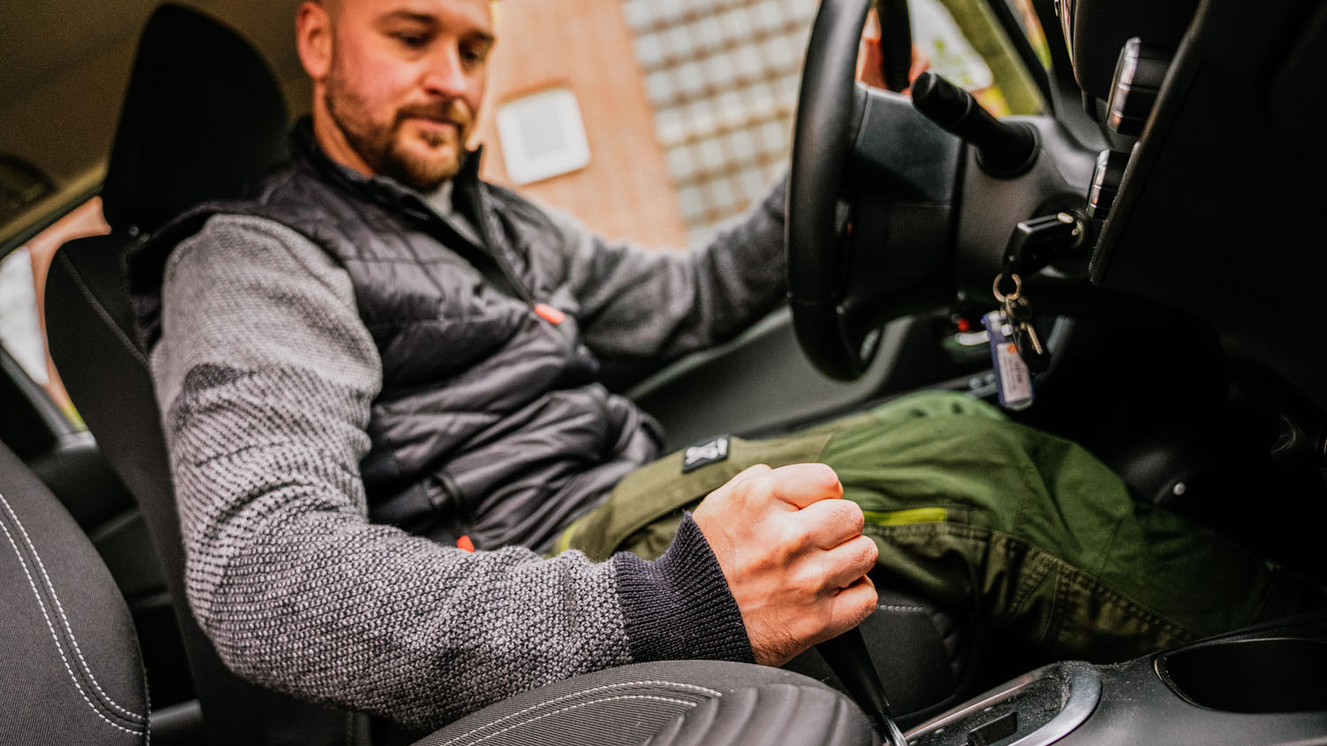Ein Mann sitzt in einem Leihwagen und bewegt den Schaltknüppel.