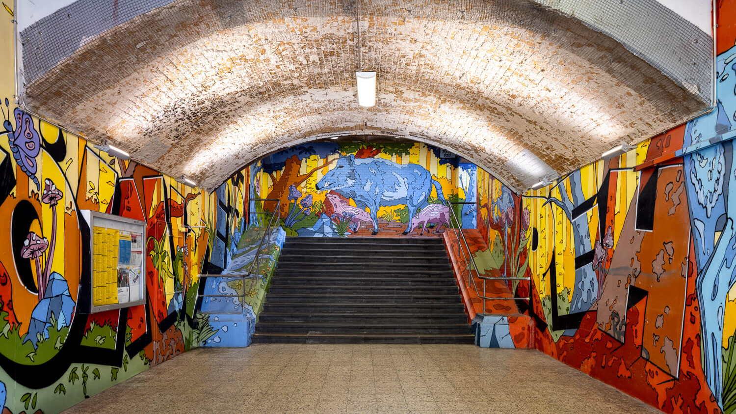 Die Unterführung am Bahnhof Köln West, die mit einer bunten Graffiti-Fantasiewelt verziert ist.