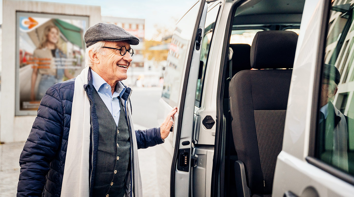 Ein älterer Herr steigt lächelnd in einen On-Demand-Kleinbus.