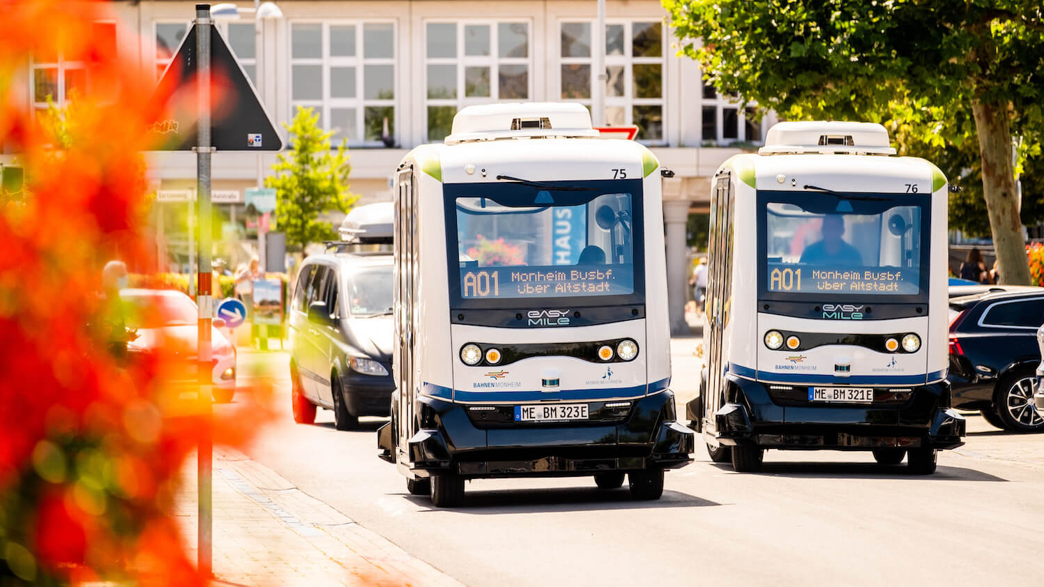 Zwei autonome Kleinbusse fahren nebeneinander auf einer Straße.