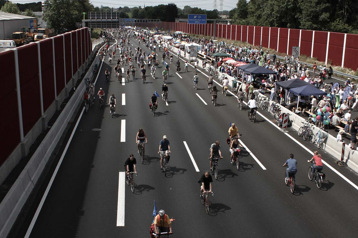 Auf der für Autos gesperrten A40 im Ruhrgebiet fahren auf der einen Seite viele Menschen auf Fahrrädern, auf der anderen Seite sind Stände für Fußgänger aufgebaut.