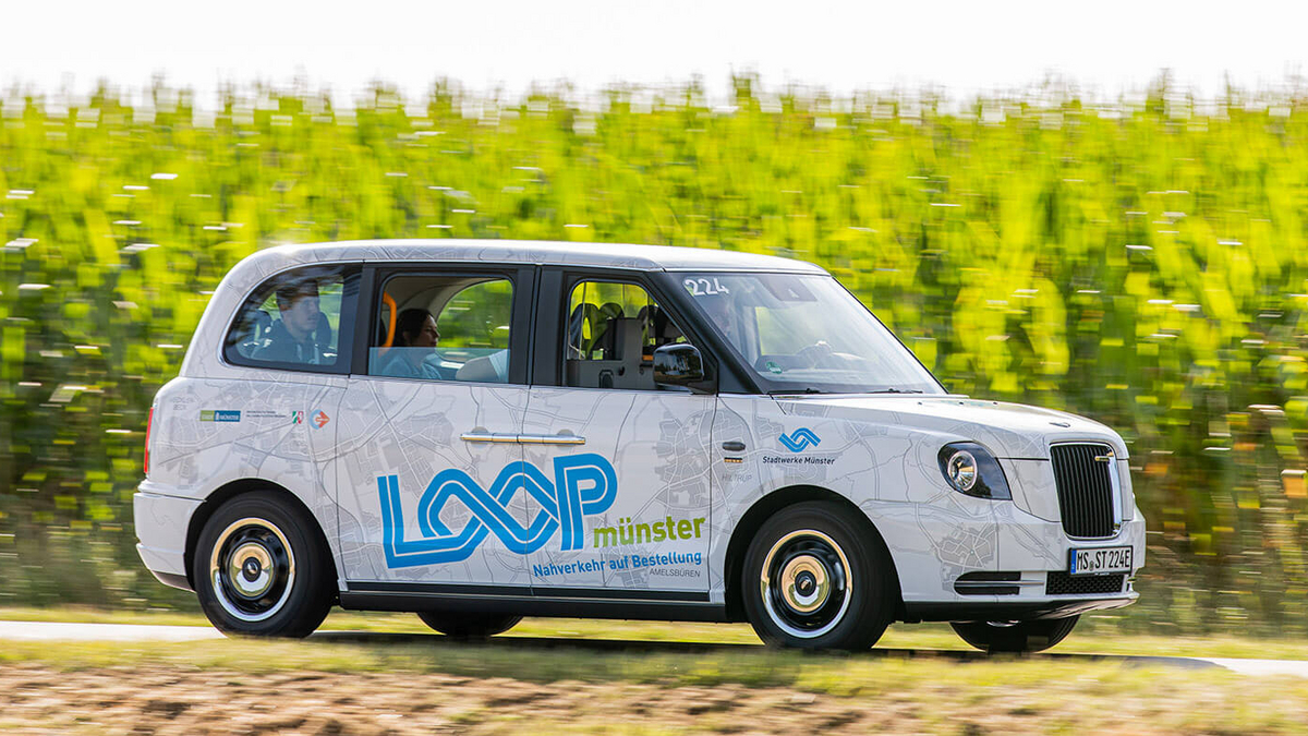 Ein Carsharing-Auto von LOOP fährt auf einer ländlichen Straße neben einem Feld entlang.
